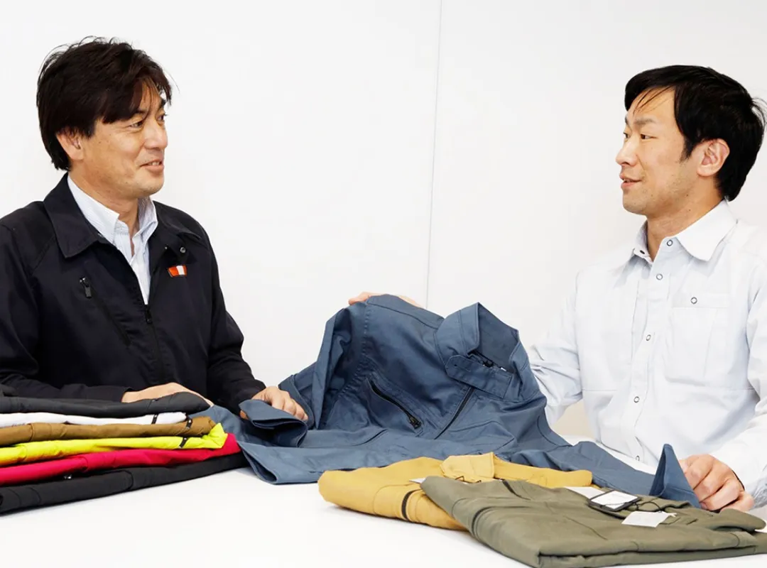 作業着を見比べながら相談する2名のスタッフ
