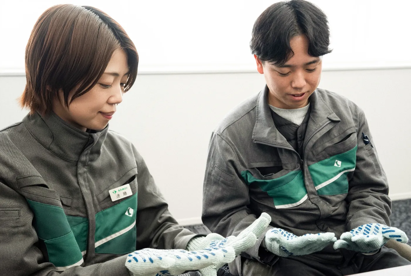 CIカラーが反映された軍手を手に取り確認するカモ井加工紙株式会社の社員